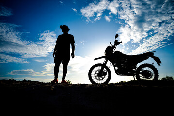 Obraz na płótnie Canvas Silhouette Man enjoying a motocross bike on a beautiful evening in the mountains.