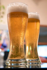 Two tall glasses of beer low angle