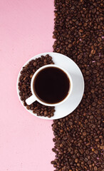 A mug with black coffee on a pink background. Half of the background is lined with coffee beans