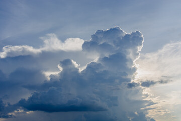 Obraz premium Large fluffy cumulus cloud in blue sky with sunlight