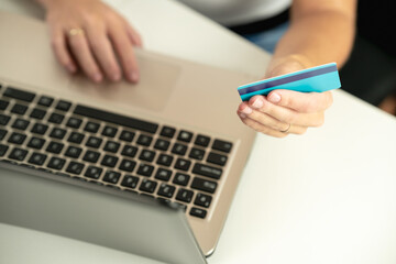 Detail of an unrecognizable woman's hand holding a credit card while shopping online with her computer - cyber monday, black friday, sales, christmas, christmas concept