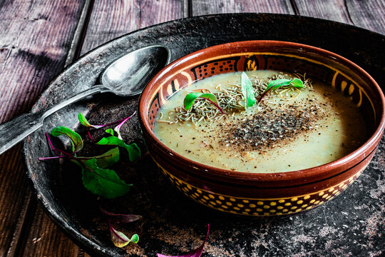 Pea soup puree with spices in a vintage dish and a plate with spices, rare cutlery, homemade food in the village
