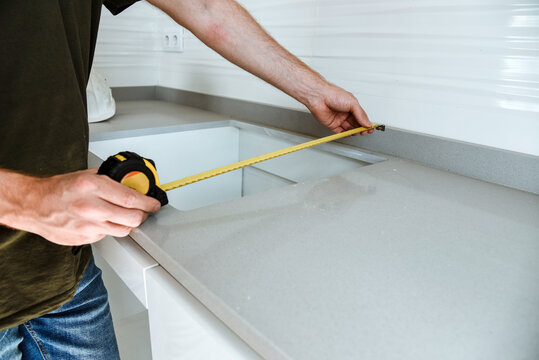 Detalle de un hombre midiendo el hueco en un mueble de cocina. Concepto de instalación de muebles a medida en un piso nuevo. Hueco para una vitrocerámica. 