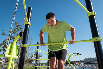 Jovem atleta a praticar exercício físico com barras num parque ao ar livre
