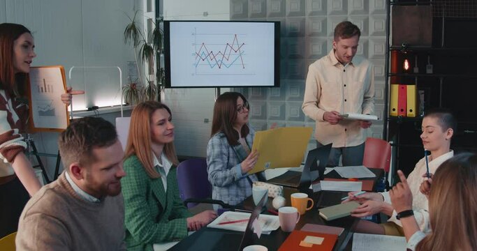Teamwork at modern office table. Group of young happy business people working together with male manager slow motion.
