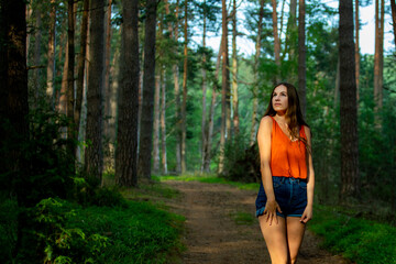 beautiful long-haired woman walks through mysterious forest; magical forest at sunset