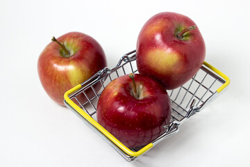Red apples on a white background. Small shopping basket full of apples