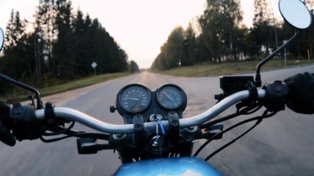 motorcycle ride on asphalt road at sunset. Hands and steering wheel.