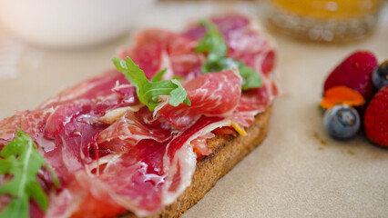 Mediterranean breakfast or brunch with a toast of serrano ham, fruit, coffee and orange juice