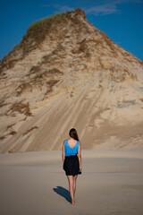 young long-haired woman with huge dunes and sandy hills in the background; woman lost in the desert