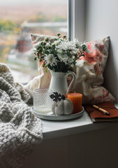 A bouquet of autumn chrysanthemum flowers in a jug, autumn cozy decor on the window. Cozy home concept