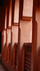 Pasillo con barandilla color rojizo, con luz del patio. Corridor with reddish railing, with light from the patio.