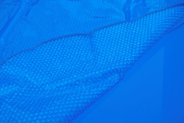 Pool cover. Blue solar film on the pool. Selective focus. Copy space. 