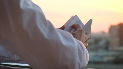 Man reading a book at sunset on the balcony, rear view