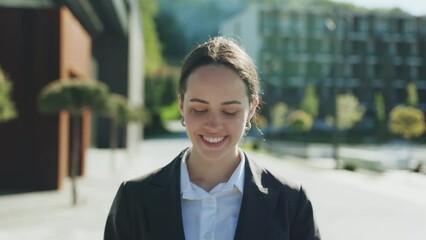 Close-up shot of cute friendly-looking young Caucasian woman holding smartphone in hands, talking, calling. Cheerful girl looking around. Walk, daytime. Sunny day. Summertime. Mobile, technology