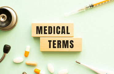 The words MEDICAL TERMS on a wooden cubes with a stethoscope and pills. Medical concept. Flat lay.