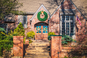 Rustic upscale brick residential home with magnolia flower wreath on double doors and large...