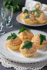 Tartlets with cheese, chicken and carrots garnished with parsley on dark gray background