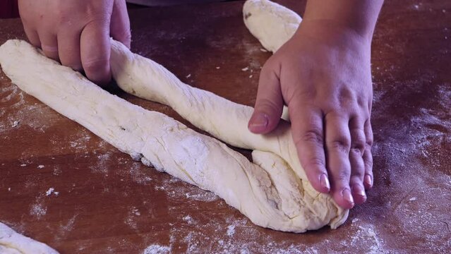 The hands of a Jewish woman weave challah dough with a pigtail for Shabbat with raisins. Medium plan