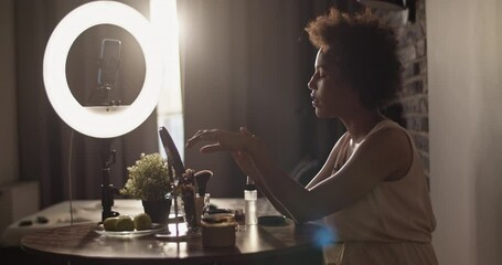 African American beauty blogger applying cream on arm