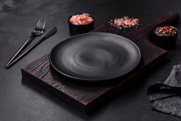 Empty black plate over dark stone background with free space. Top view