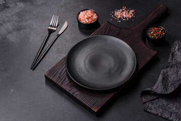 Empty black plate over dark stone background with free space. Top view