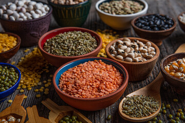 Vegan protein source.Various assortment of legumes, lentils, chickpea and beans assortment in different bowls on wooden table. Top view.