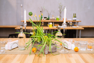 A rustic table set. Bottles of drinking water, candles, fresh fruit and glasses on a wicker napkin.