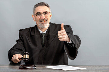 Judge showing thumbs up, judge's gavel on the table. Law Lord wearing gown using a hammer for attention and verdict, justice judgment at courts of law