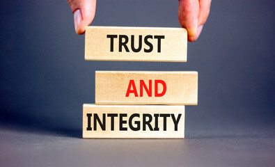 Trust and integrity symbol. Concept words Trust and integrity on wooden blocks. Businessman hand....