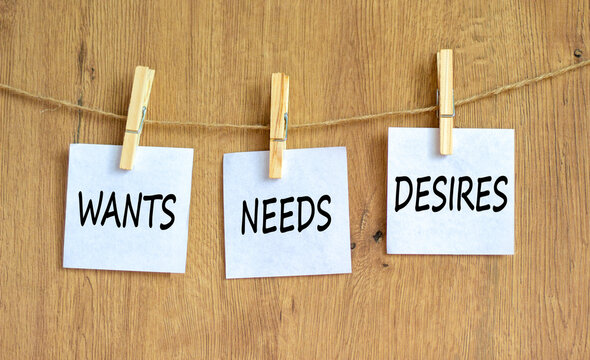 Wants needs and desires symbol. Concept words Wants Needs Desires on white papers on wooden clothespins. Beautiful wooden background. Business wants needs desires concept. Copy space.
