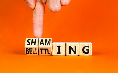 Shaming and belittling symbol. Concept words Shaming and Belittling on wooden cubes. Businessman...