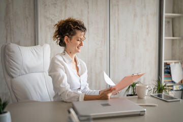 Obraz premium One young business woman working in the office holding clipboard