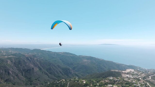 Adrenaline outdoor sport. Beautiful tranquil and calm time in nature above Malibu. Two paragliders flying over mountain top in epic summer day light. Parachutes or paragliding extreme sport experience
