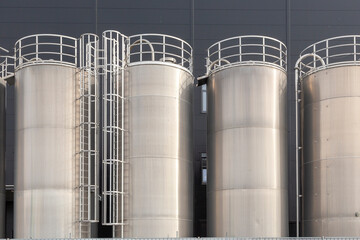 chrome silos in front of generic grey wall of a plant
