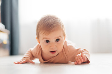 A small child crawls on the floor. Child 6 months