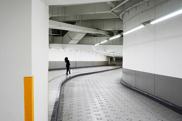 Woman walking down ramp through the underground parking lot