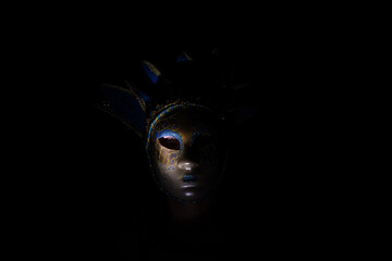 The face of a girl in a Venetian carnival mask in the dark, a masquerade and an actor in a mask