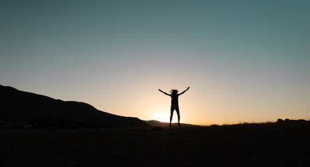 Fototapeta na wymiar girl jumping at sunset in the mountains