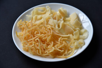 Salted squid appetizer for beer on a white plate. Delicious straws of spicy squid on a black background.