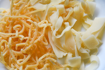 Salted squid appetizer for beer on a white plate. Delicious straws of spicy squid on a black background.