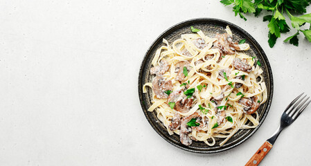 Mushroom Tagliatelle Pasta with parmesan cheese and cream sauce on white background, top view. Prepared italian pasta with champignon on gray plate