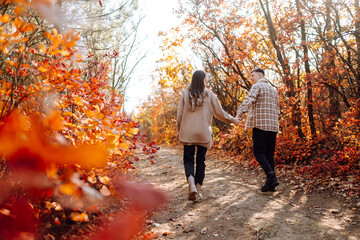 Happy couple in love newlyweds in casual clothes travel together, hike and walk in the autumn forest in nature.