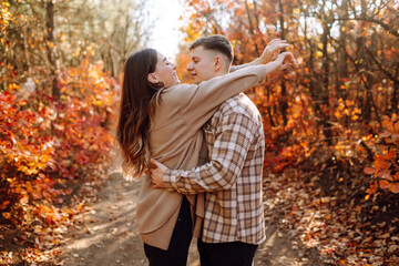 Fototapeta premium Happy couple in love newlyweds in casual clothes travel together, hike and walk in the autumn forest in nature.