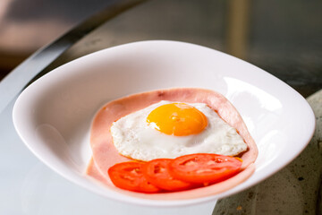 Huevo frito sobre rebanadas de jamón y jitomate rebanado 