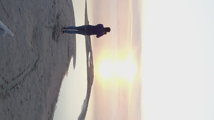 Vertical video. A female photographer came to the shore of Lake Svityaz. Photographs the morning fog and sunrise. Shot on a drone.
