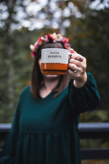 Woman hand holding coffee cup in nature in the fall.