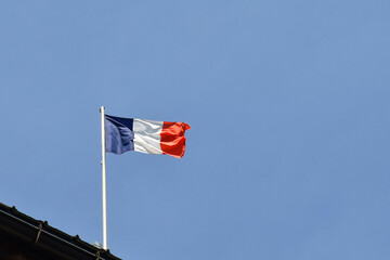 A French flag flies on top of a roof against the blue sky, Chamonix-Mont-Blanc, Haute Savoie, France
