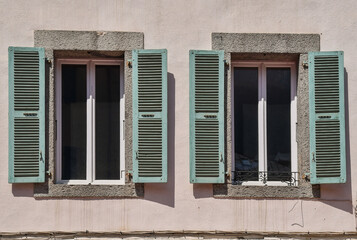 Fototapeta premium A pair of windows with pale green shutters and stone frames, France