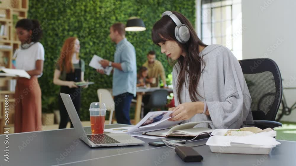 Poster woman, laptop and notebook at tech startup writing notes on desk while listening to radio. girl, mus